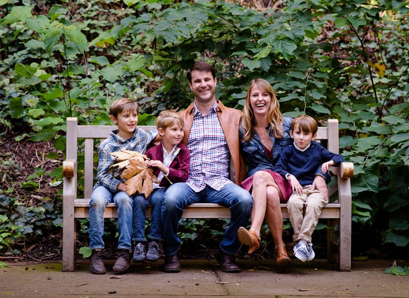 The Paradise Teak Family sitting on an outdoor teak bench surrounded by greenery Paradise Teak Bay Area California